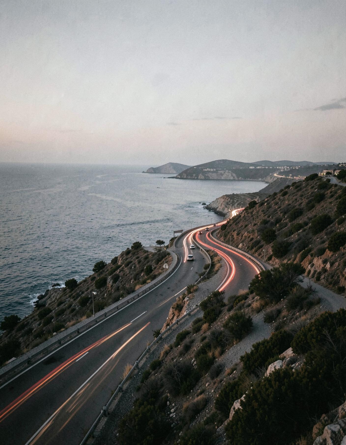 An empty coastal highway curving along the Cyprus shoreline at dusk
